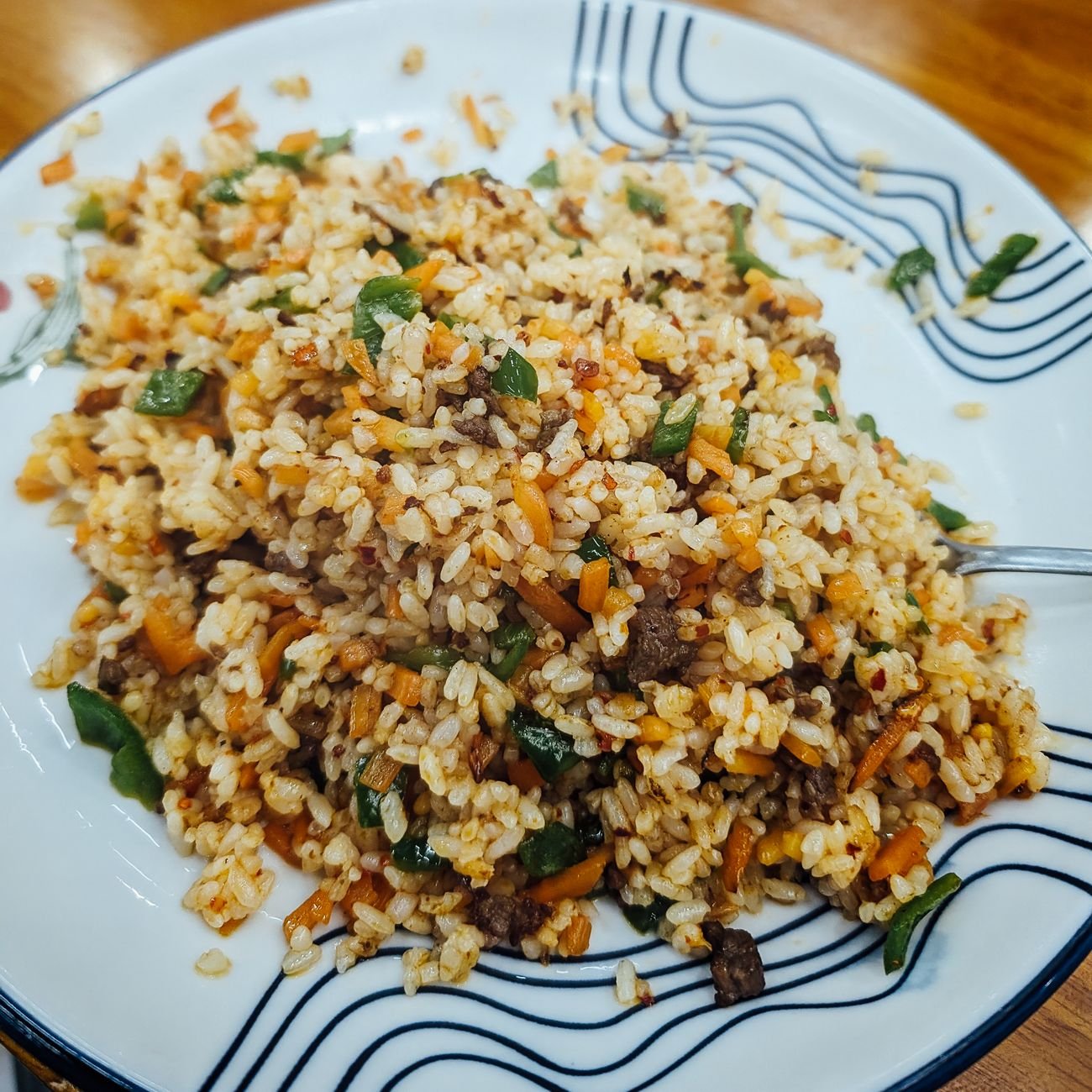 A plate of colorful homemade fried rice served on a decorated dish.